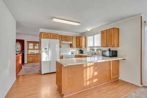 Kitchen featuring sink, light wood-type flooring, white appliances, and kitchen peninsula