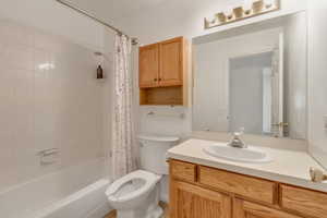 Full bathroom with shower / bath combination with curtain, vanity, and toilet