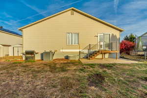 Rear view of property with a yard, a storage unit, a trampoline, cooling unit, and a patio area