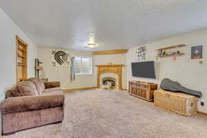 Carpeted living room featuring a tile fireplace and a textured ceiling