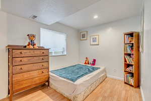 Bedroom with a textured ceiling and light hardwood / wood-style flooring