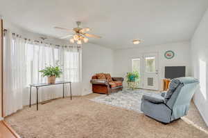 Carpeted living room featuring ceiling fan