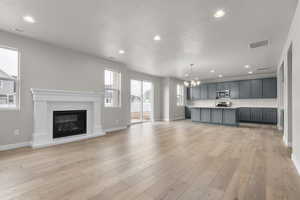 Unfurnished living room featuring a notable chandelier and light wood-type flooring