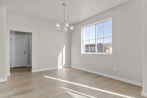 Empty room with an inviting chandelier and light hardwood / wood-style flooring