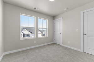 Empty room with light colored carpet and a textured ceiling