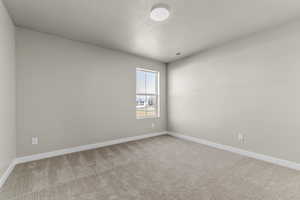 Unfurnished room featuring light carpet and a textured ceiling