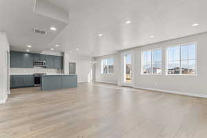 Unfurnished living room featuring an inviting chandelier, sink, light hardwood / wood-style flooring, and a textured ceiling