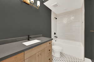 Full bathroom with tile patterned floors, vanity, toilet, and tiled shower / bath combo