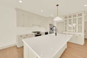 Kitchen featuring appliances with stainless steel finishes, light wood-type flooring, decorative light fixtures, and sink