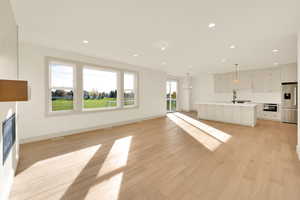 Unfurnished living room with light hardwood / wood-style flooring and sink