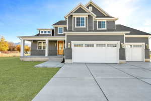 View of front of house featuring a porch, a garage, and a front lawn