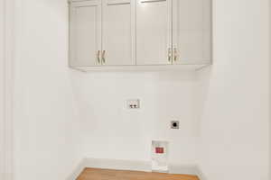 Laundry room featuring hookup for an electric dryer, cabinets, wood-type flooring, and hookup for a washing machine