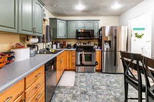 Kitchen with appliances with stainless steel finishes, a textured ceiling, and sink