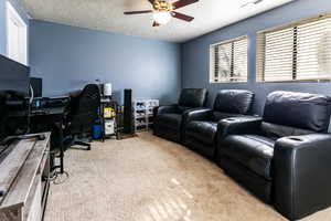 Home office with a textured ceiling, ceiling fan, and light carpet