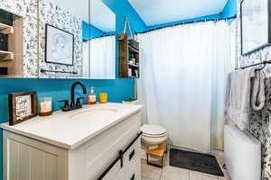 Bathroom with tile patterned floors, walk in shower, vanity, and toilet