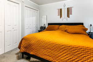 Bedroom with crown molding, carpet floors, and two closets