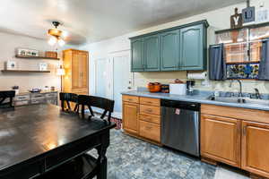 Kitchen featuring stainless steel dishwasher, ceiling fan, sink, and a textured ceiling