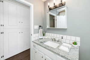 Bathroom featuring vanity, decorative backsplash, and wood-type flooring