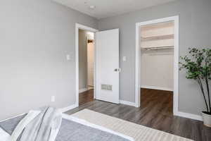 Bedroom featuring dark hardwood / wood-style floors, a walk in closet, a textured ceiling, and a closet