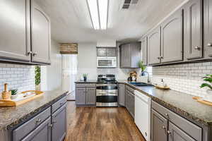 Kitchen featuring gray cabinetry, white appliances, backsplash, sink, and dark hardwood / wood-style floors