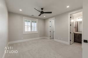 Unfurnished bedroom with ensuite bathroom, ceiling fan, and light carpet