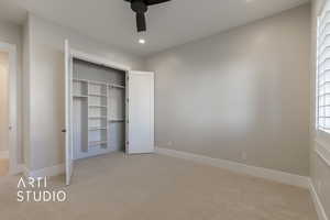 Unfurnished bedroom featuring ceiling fan, light colored carpet, and a closet