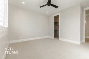 Unfurnished bedroom featuring a spacious closet, a closet, ceiling fan, and light colored carpet