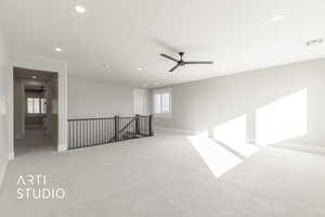 Spare room featuring plenty of natural light, ceiling fan, and light colored carpet