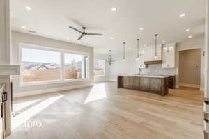 Kitchen featuring light wood-type flooring, a brick fireplace, a spacious island, sink, and white cabinets