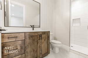 Bathroom with a tile shower, vanity, and toilet