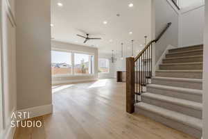 Staircase featuring hardwood / wood-style floors and ceiling fan with notable chandelier