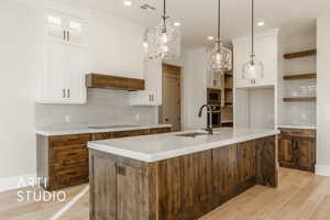 Kitchen with an island with sink, white cabinetry, stainless steel appliances, and sink