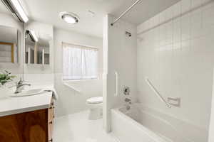 Full bathroom featuring vanity, tiled shower / bath, tile patterned flooring, toilet, and tile walls