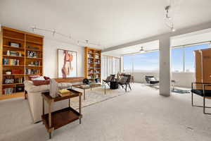 Living room featuring ceiling fan, light colored carpet, and rail lighting