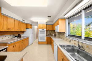 Kitchen featuring tasteful backsplash, sink, and white appliances