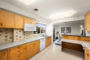 Kitchen with kitchen peninsula, sink, white appliances, and backsplash