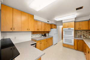 Kitchen with decorative backsplash and white appliances