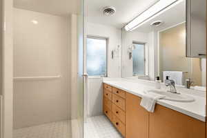 Bathroom with tile patterned flooring, vanity, and tiled shower