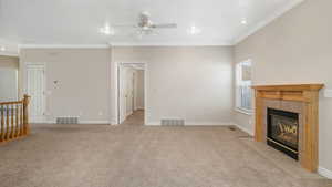 Unfurnished living room featuring light carpet, a fireplace, ornamental molding, and ceiling fan