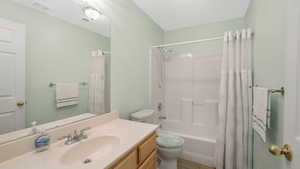 Full bathroom with toilet, shower / bath combination with curtain, vanity, and tile patterned floors