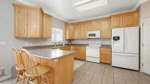 Kitchen with kitchen peninsula, white appliances, crown molding, and sink