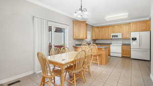 Kitchen featuring pendant lighting, white appliances, ornamental molding, a notable chandelier, and a kitchen island