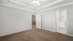 Unfurnished bedroom with light colored carpet, ensuite bath, ceiling fan, and crown molding