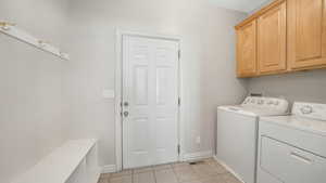 Laundry room featuring light tile patterned flooring, cabinets, and independent washer and dryer