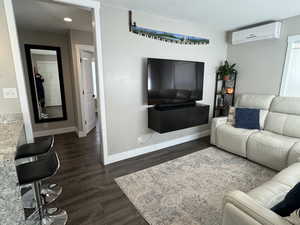 Living room featuring a textured ceiling, dark hardwood / wood-style floors, and an AC wall unit