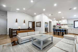 Living room with light hardwood / wood-style floors and vaulted ceiling