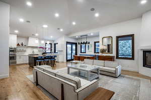 Living room with a large fireplace, light hardwood / wood-style flooring, and sink