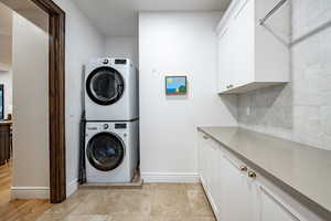 Laundry area featuring stacked washer / dryer, cabinets, and light hardwood / wood-style floors