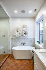 Bathroom with tile patterned floors, vanity, tile walls, and independent shower and bath