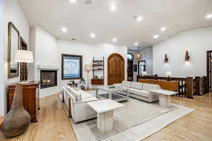 Living room with a fireplace, light hardwood / wood-style floors, and vaulted ceiling